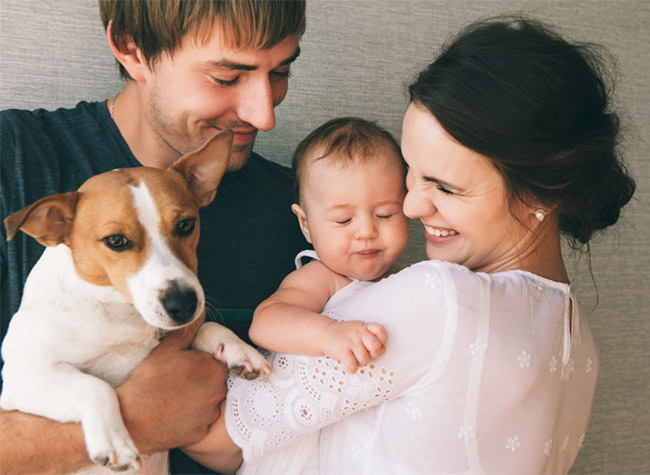 Man holding a dog and a woman holding a baby